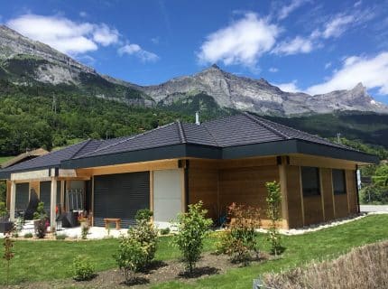 Maison en ossature bois à Passy avec terrasse aménagée, jardin et menuiseries aluminium, entourée de montagnes