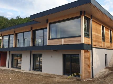 Maison en bois contemporaine à Annecy avec bardage bois, grandes baies vitrées et toit plat